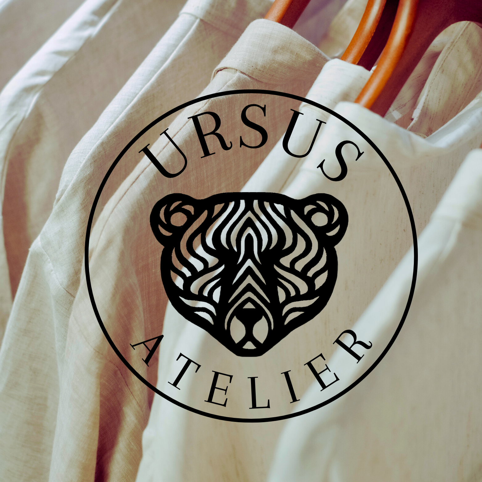 Ursus Atelier logo on a beige garment with a blurred background